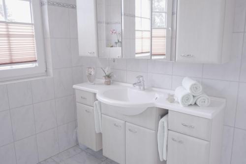 a white bathroom with a sink and a mirror at Haus Sabine - OG in Groß Kirr