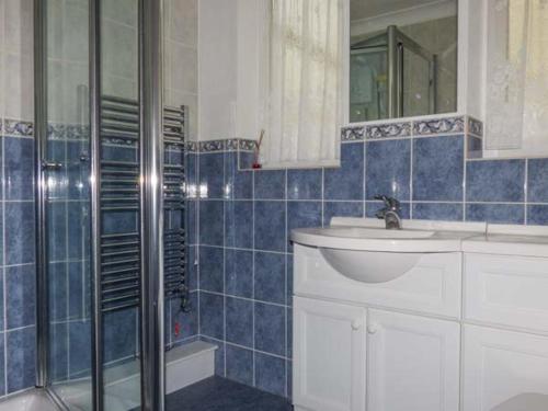 a blue tiled bathroom with a sink and a shower at Skylark in Holt