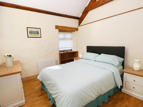 a bedroom with a large white bed and a window at Stable Cottage in Clynderwen