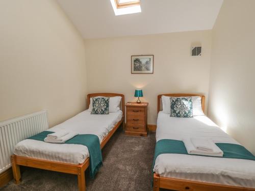 two twin beds in a room with a night stand at Calf House in Sutton