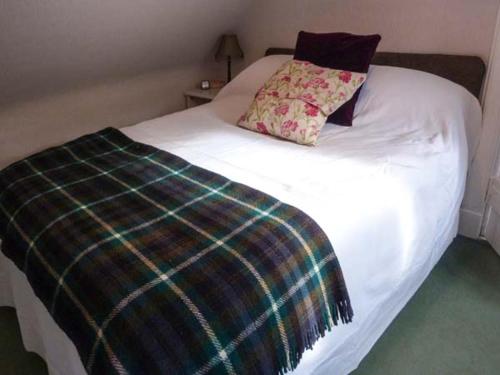 uma cama branca com um cobertor xadrez em Riemore em Tomintoul