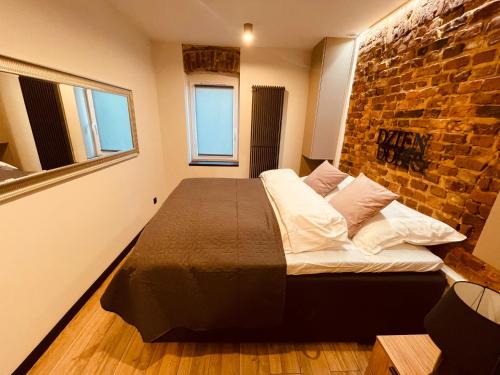 una camera con un grande letto con un muro di mattoni di Apartamenty KTW Park Śląski - Family DELUX a Katowice