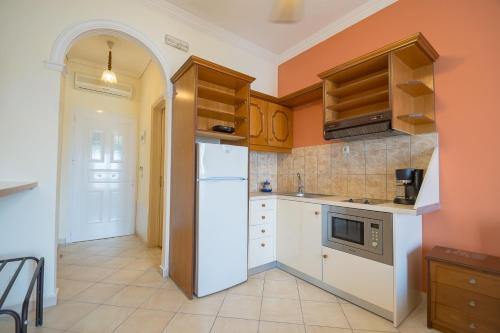 a kitchen with a white refrigerator and wooden cabinets at Mazis Apartments in Agios Gordios