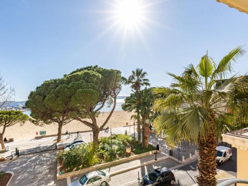 een uitzicht op een strand met palmbomen en auto's bij Apartment Les Sirènes by Interhome in Sainte-Maxime