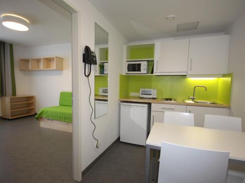 a kitchen with white cabinets and green walls at Apartment smart living by Interhome in Sankt Ulrich