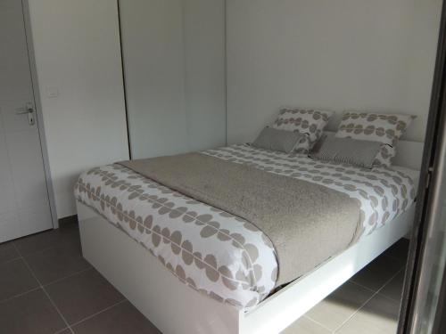 a white bedroom with a bed with gray pillows at Apartment Le Golf Clair-14 by Interhome in Saint-Cyprien
