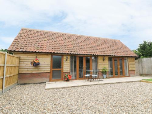 a small wooden house with a table and a fence at Foxley Wood Cottage in Horsham Saint Faith