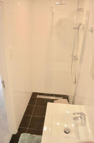 uma casa de banho branca com um chuveiro e um lavatório. em De Wulk 26 em Zandvoort