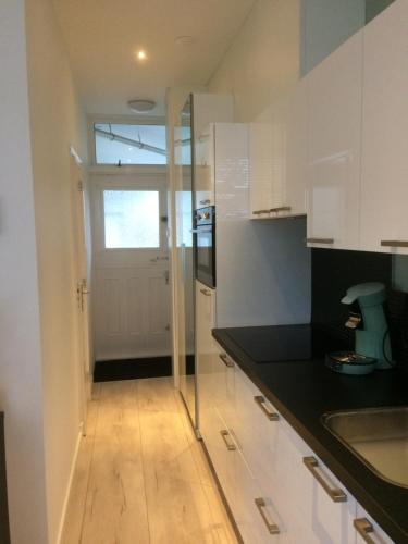 uma cozinha com armários brancos e uma porta de vidro em De Wulk 26 em Zandvoort