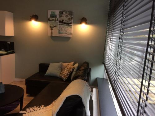 uma sala de estar com um sofá e uma janela com persianas em De Wulk 26 em Zandvoort
