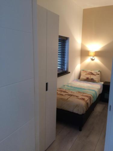 um pequeno quarto com uma cama e um closet em De Wulk 26 em Zandvoort