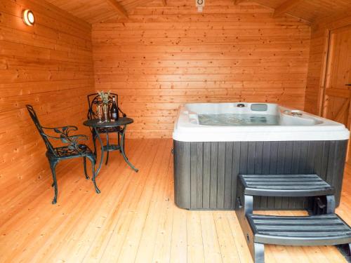 a hot tub in a room with a chair and a table at Cropvale Lodge in Charlton