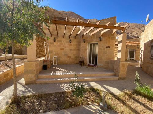 a patio of a house with a wooden pergola at Afra Hot Springs Chalets in Tufailah