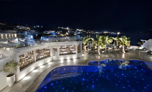 a view of a building with a pool at night at Petinos Beach Hotel in Platis Gialos