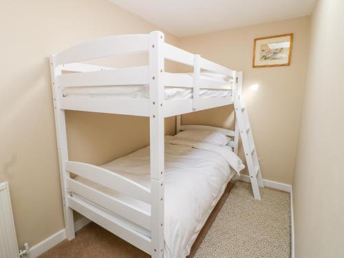 East WittonにあるOrchard Cottageのハシゴ付きの小さな部屋の白い二段ベッド1台分です。