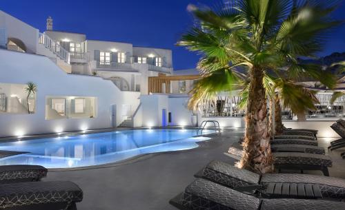 a swimming pool with a palm tree in front of a house at Petinos Beach Hotel in Platis Yialos Mykonos