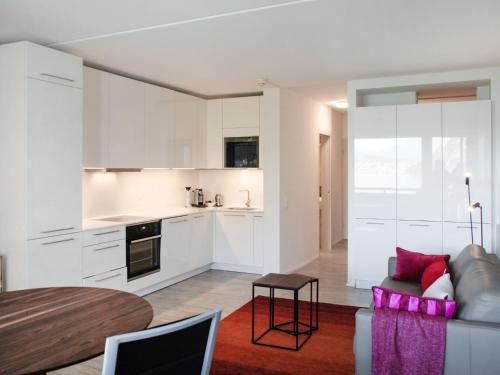 a kitchen and living room with white cabinets and a table at Apartment App- 511 by Interhome in Bissone