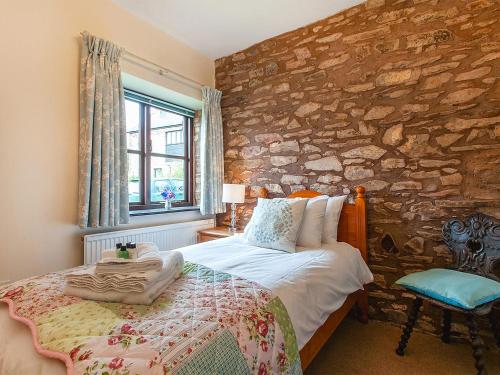 a bedroom with a bed and a stone wall at Rainsbury House in Taunton