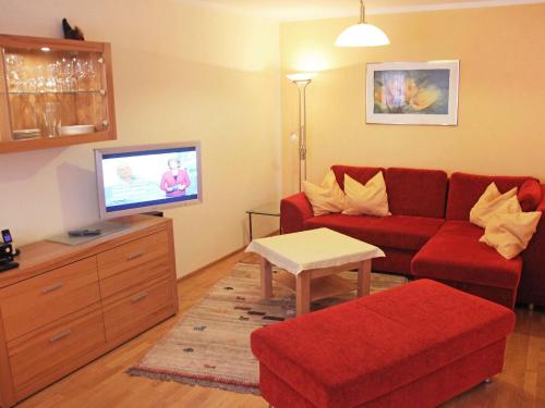 ein Wohnzimmer mit einem roten Sofa und einem Flachbild-TV in der Unterkunft Apartment Bibelöd-6 by Interhome in Ruhpolding