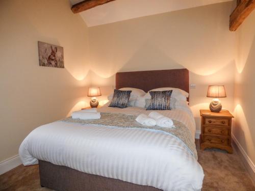 1 dormitorio con 1 cama grande y 2 lámparas en Cow Hill Laith Barn, en Sawley