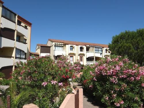 un bâtiment avec des fleurs roses devant lui dans l'établissement Apartment Les Mas de La Mer-15 by Interhome, à Saint Cyprien Plage