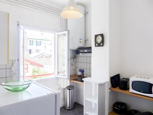 une cuisine blanche avec une fenêtre et un four micro-ondes dans l'établissement Apartment St jean by Interhome, à Biarritz