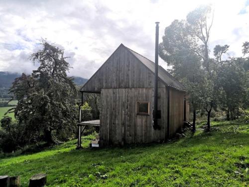 an old wooden barn in a field of grass at Tři domky - tiny houses in Děpoltice