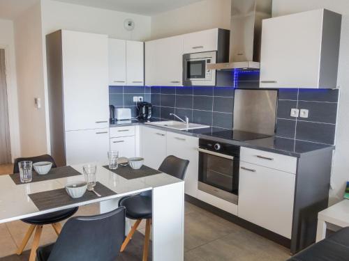 une cuisine avec des armoires blanches et une table avec des chaises dans l'établissement Apartment Terrasse de Lucie by Interhome, à Saint-Cyprien