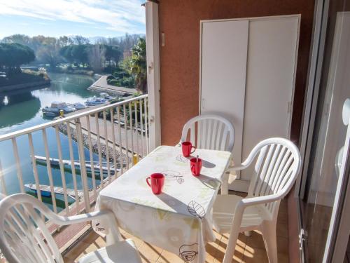 une table et des chaises sur un balcon avec vue sur une rivière dans l'établissement Apartment Marina Village-5 by Interhome, à Saint Cyprien Plage