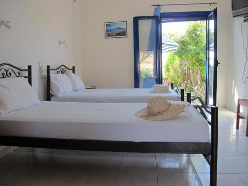 two beds in a room with a hat on a table at Porto Kastri Studios in Kastrí