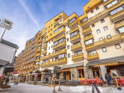 un grand bâtiment jaune avec des tables devant lui dans l'établissement Apartment Vanoise 152 by Interhome, à Val Thorens