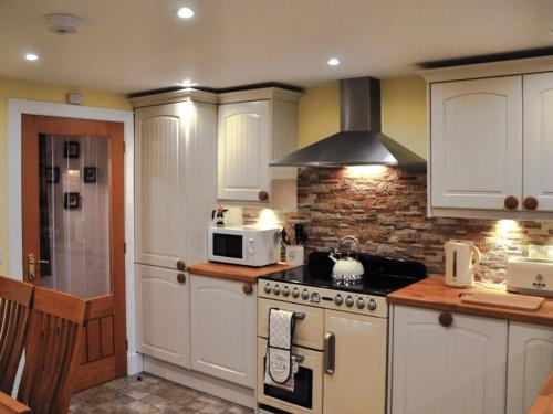 a kitchen with a stove and a microwave at Holiday Home Glenn Cottage by Interhome in Uig