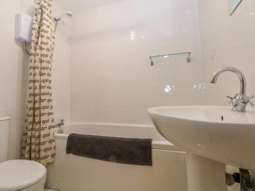 a white bathroom with a sink and a toilet at Bowden Head Farmhouse Cottage in Highpeak Junction