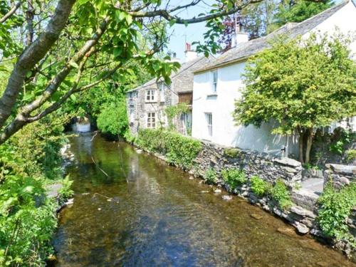 a river in front of a house and a building at 2 Cark House in Holker