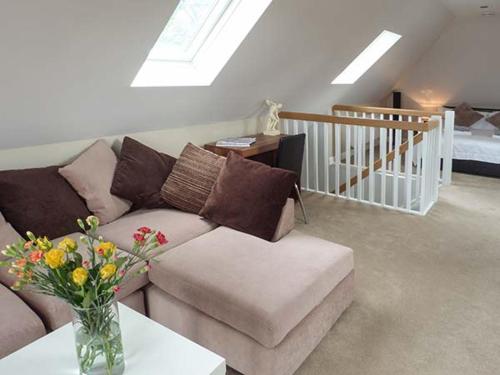 uma sala de estar com um sofá e um vaso com flores em The Willows em Canterbury