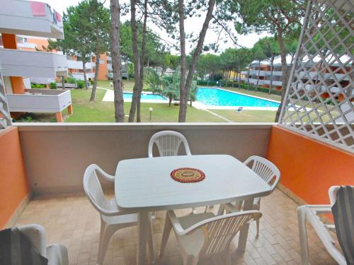 un tavolo bianco con sedie su un balcone con piscina di Apartment Solarium-3 by Interhome a Bibione