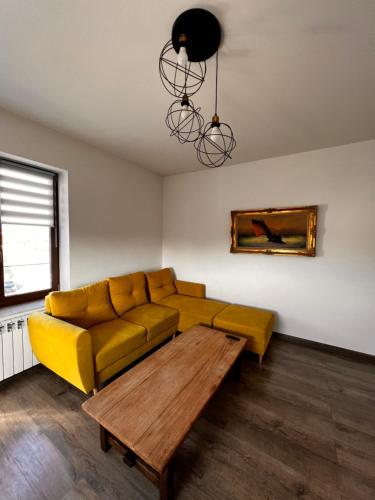 sala de estar con sofá amarillo y mesa de madera en Apartamenty na 1 Maja, en Skierniewice