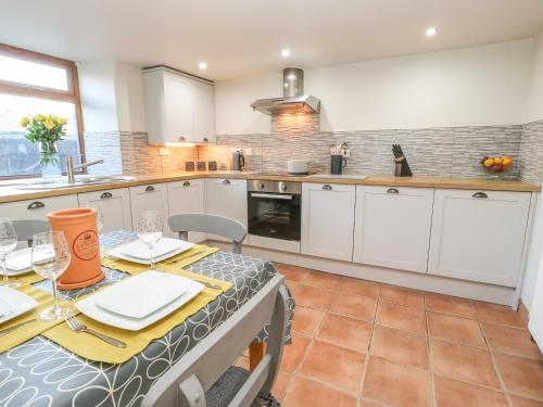 a kitchen with white cabinets and a table and chairs at Boshaw Cottage in Holmfirth
