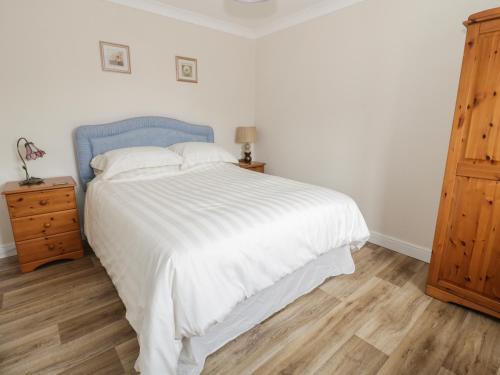 a bedroom with a white bed and a wooden dresser at Bedlinog in Amlwch