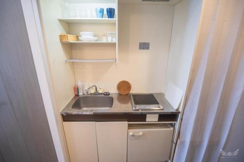 eine kleine Küche mit Spüle und Herd in der Unterkunft Escort Haruyoshi in Fukuoka