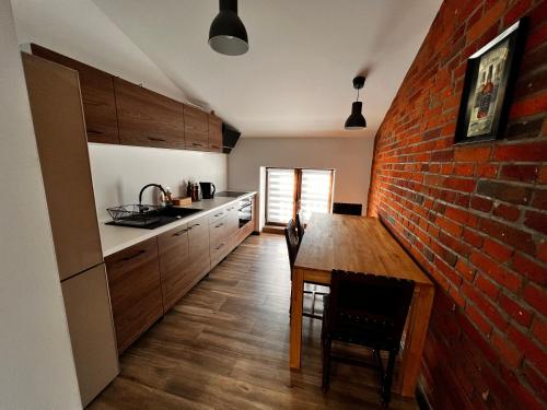 een keuken met een bakstenen muur en een houten tafel bij Apartamenty na 1 Maja in Skierniewice