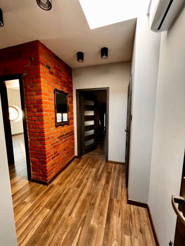 Habitación vacía con pared de ladrillo y suelo de madera. en Apartamenty na 1 Maja, en Skierniewice