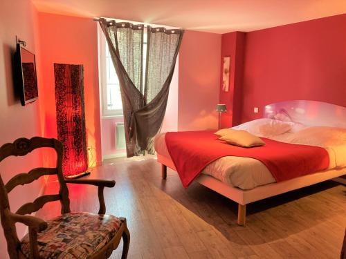 a bedroom with red walls and a bed and a chair at La Terrasse in Saugues