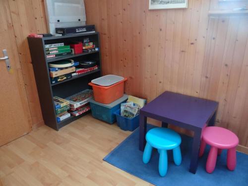 ein Spielzeugzimmer mit einem Tisch und zwei Hockern in der Unterkunft Apartment Chalet Fluegärtli by Interhome in Gerschnialp
