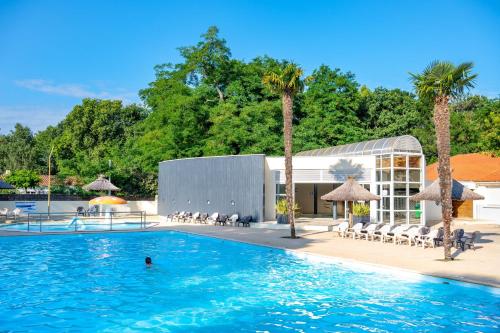 une piscine dans un hôtel avec des palmiers dans l'établissement Flower Camping Les Biches, à Saint-Hilaire-de-Riez