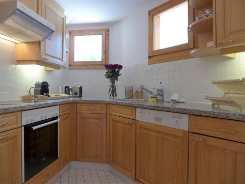 a kitchen with wooden cabinets and white appliances at Apartment Chesa Fuolla Verda A8 by Interhome in Celerina