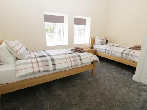 a bedroom with two beds and two windows at White Rose Cottage in Guisborough