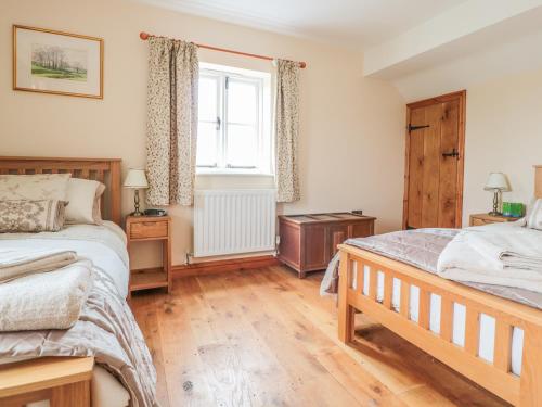 a bedroom with two beds and a window at Orchard Cottage in Tenbury