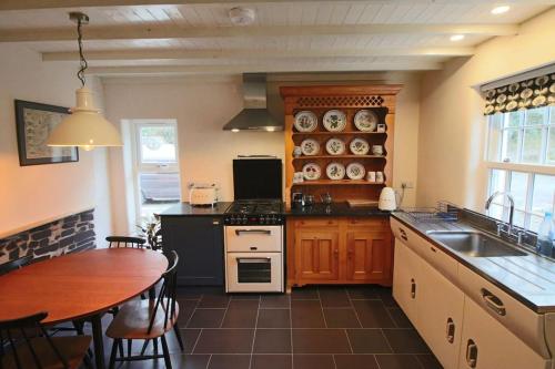 eine Küche mit Tisch und Herd oberen Backofen in der Unterkunft Riverside cottage walking distance into Caernarfon in Caernarfon