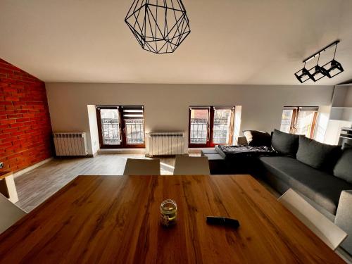 salon z kanapą i drewnianym stołem w obiekcie Apartament na 1 Maja -4- w mieście Skierniewice